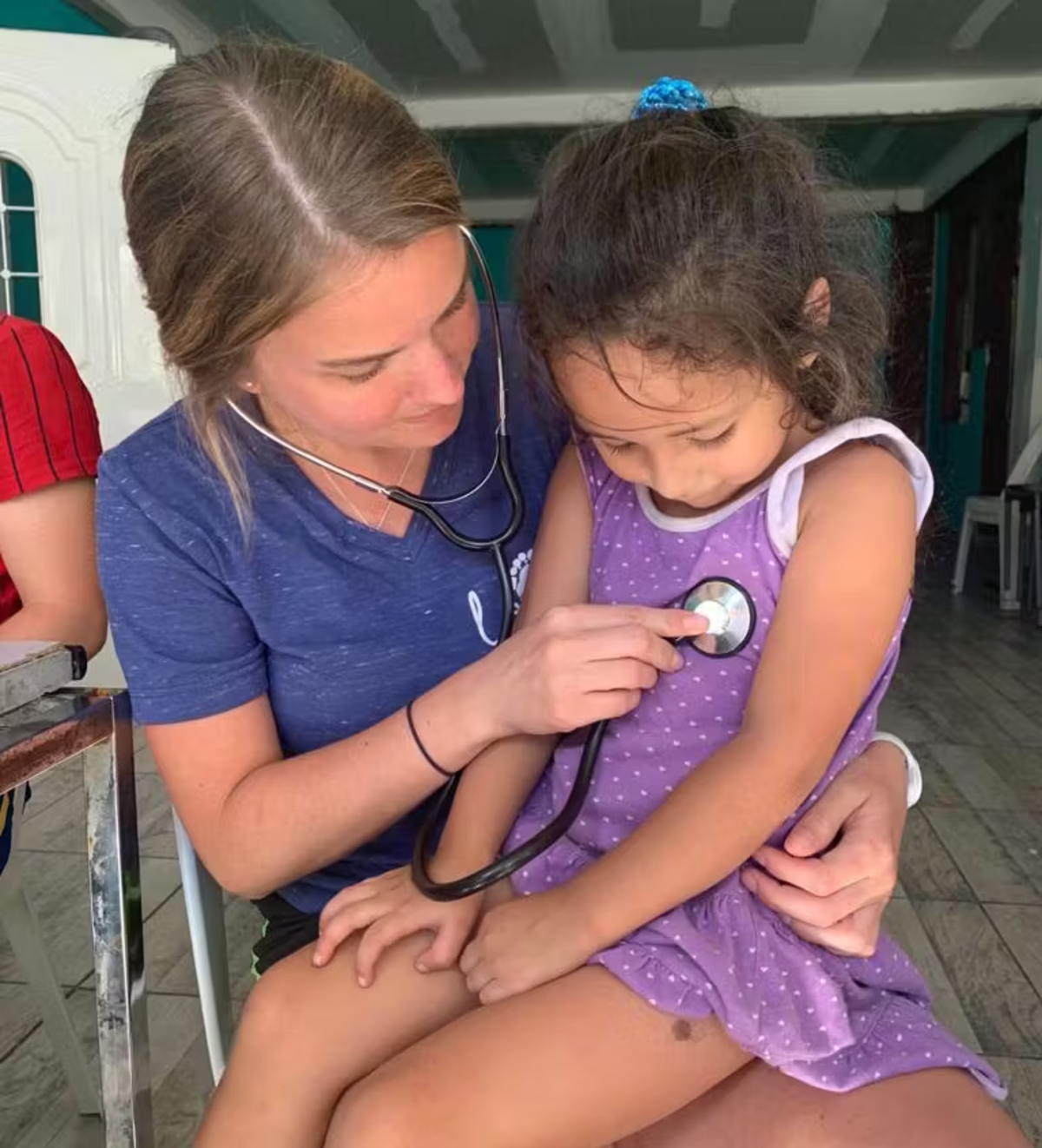 IBHQ Volunteer using a stethoscope in a checkup for a little girl
