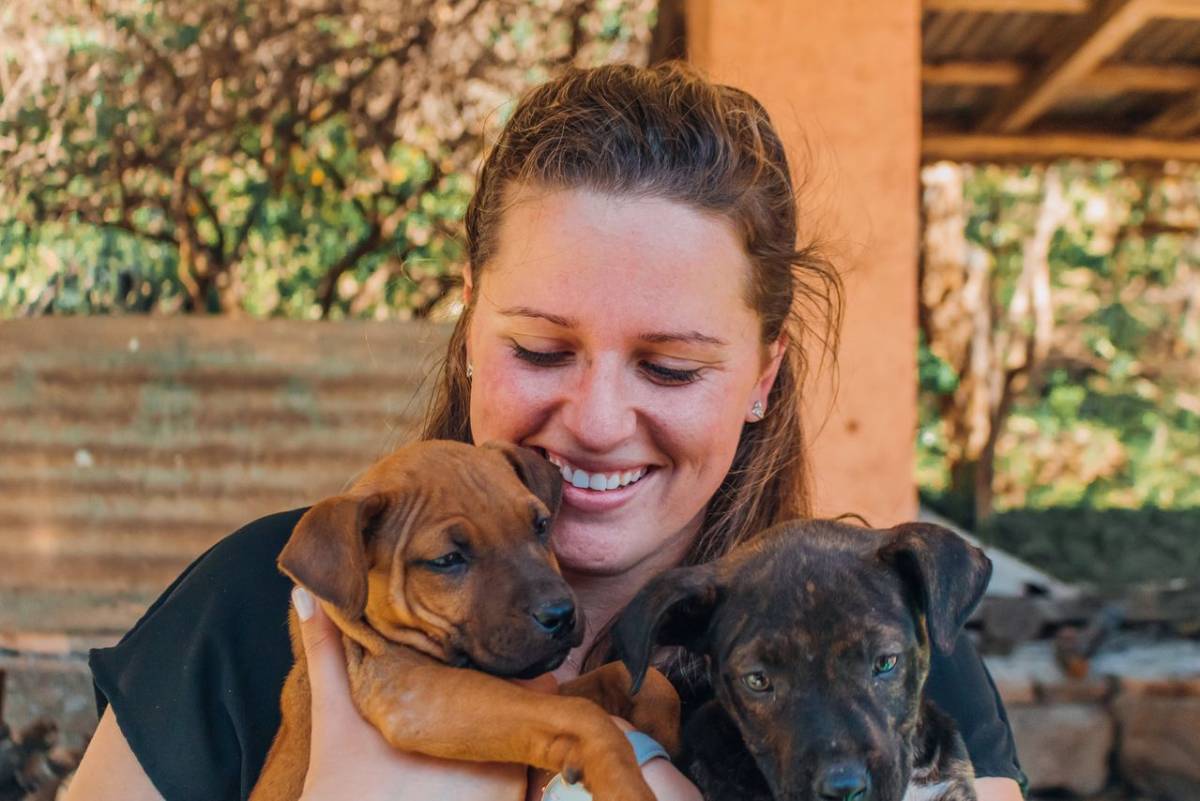 IVHQ Volunteer holding two young puppies