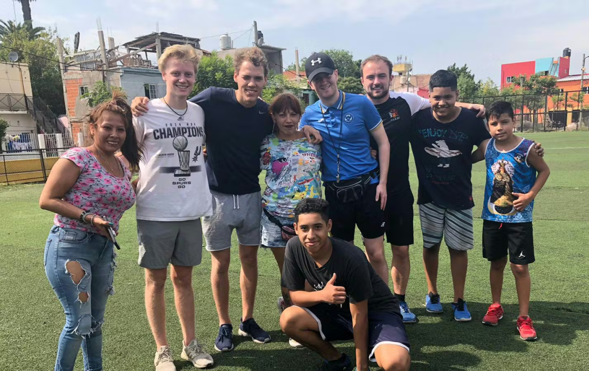 IVHQ Volunteer posing with a class of children on a sports field