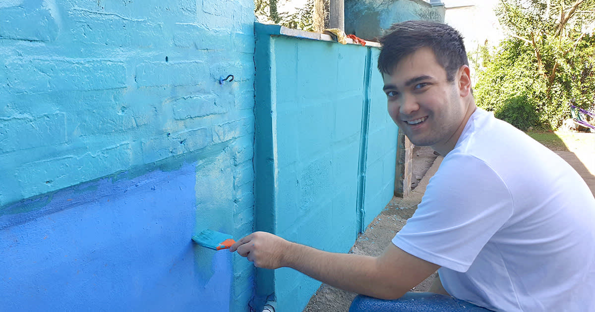 IVHQ Volunteer repainting a brick wall light blue in Argentina