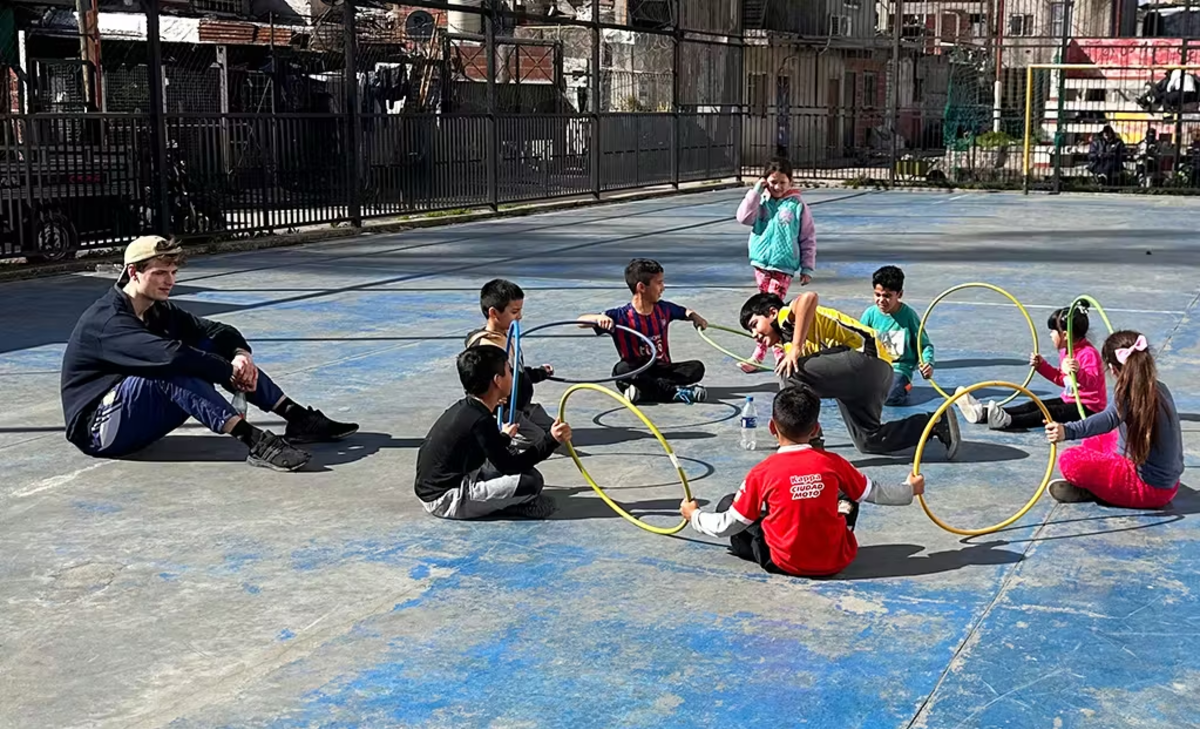 IVHQ Volunteer teaching a class of kids a game involving hula hoops