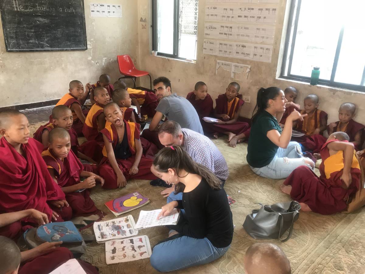 monk children and volunteers sitting on the floor