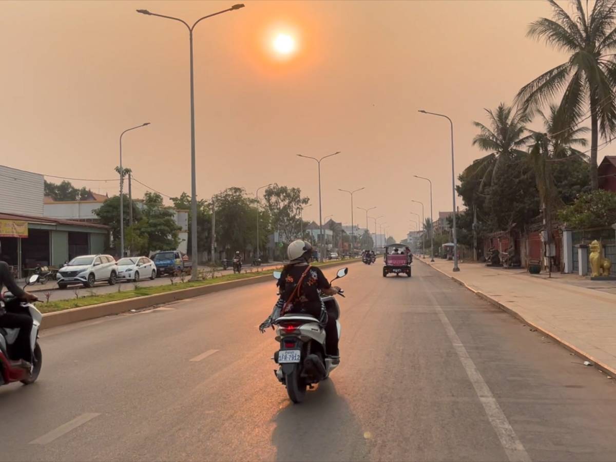 Moped driving down a road in Southeast Asia at sunset.