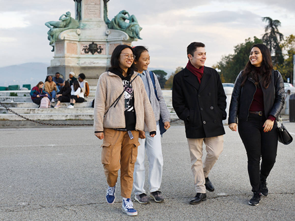 NYU students smiling and walking in front of a monument