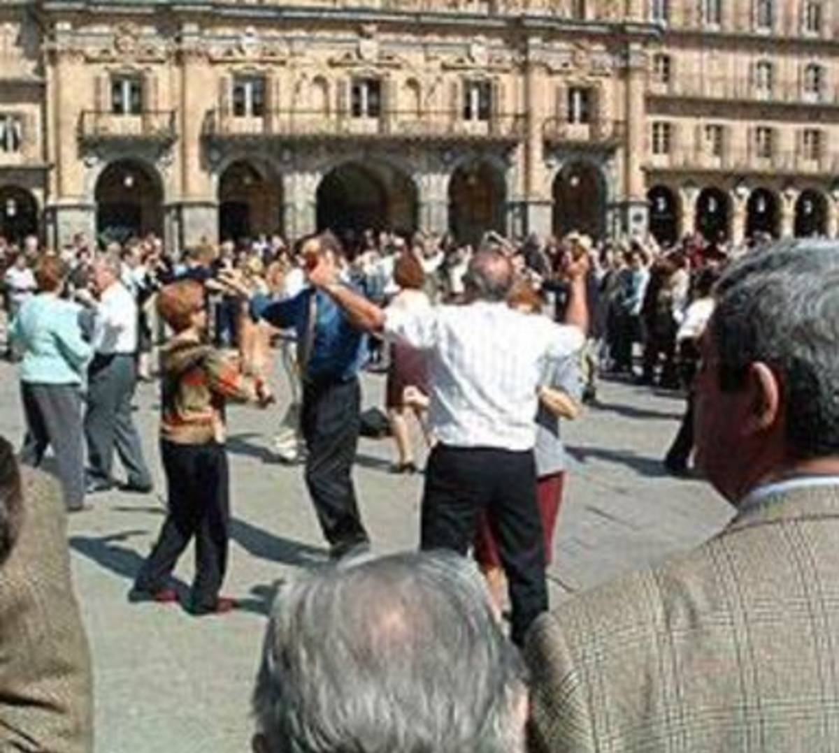 People joyfully dancing in square in front of huge building.