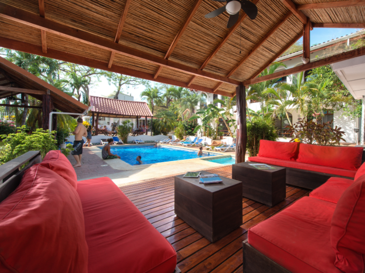 Shaded lounge with red sofas overlooking the pool at EF Playa Tamarindo, where students relax, swim, and enjoy the tropical Costa Rican atmosphere.