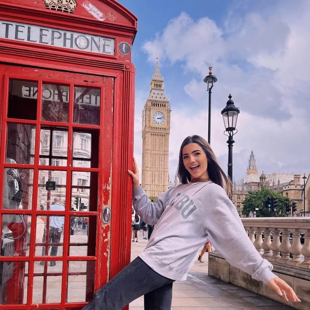 Student in front of Big Ben next to a red phonebox. 