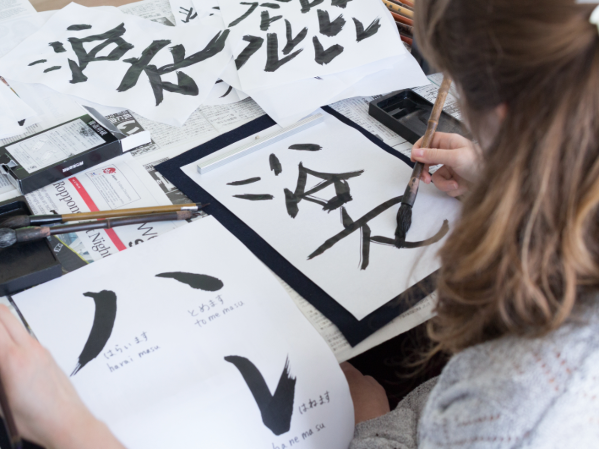 Student practicing Japanese calligraphy with brush and ink during a cultural class in Tokyo.