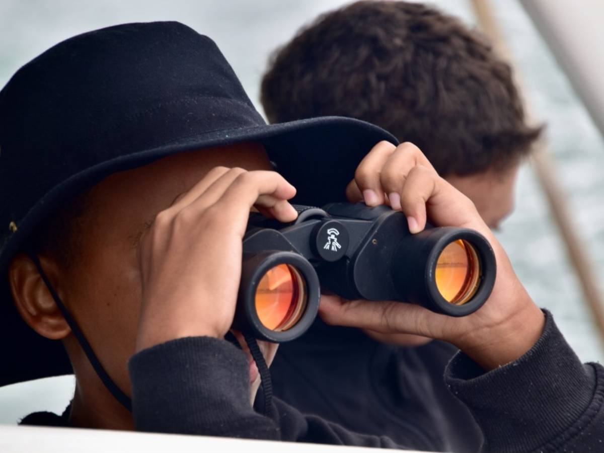 student with binoculars on boat