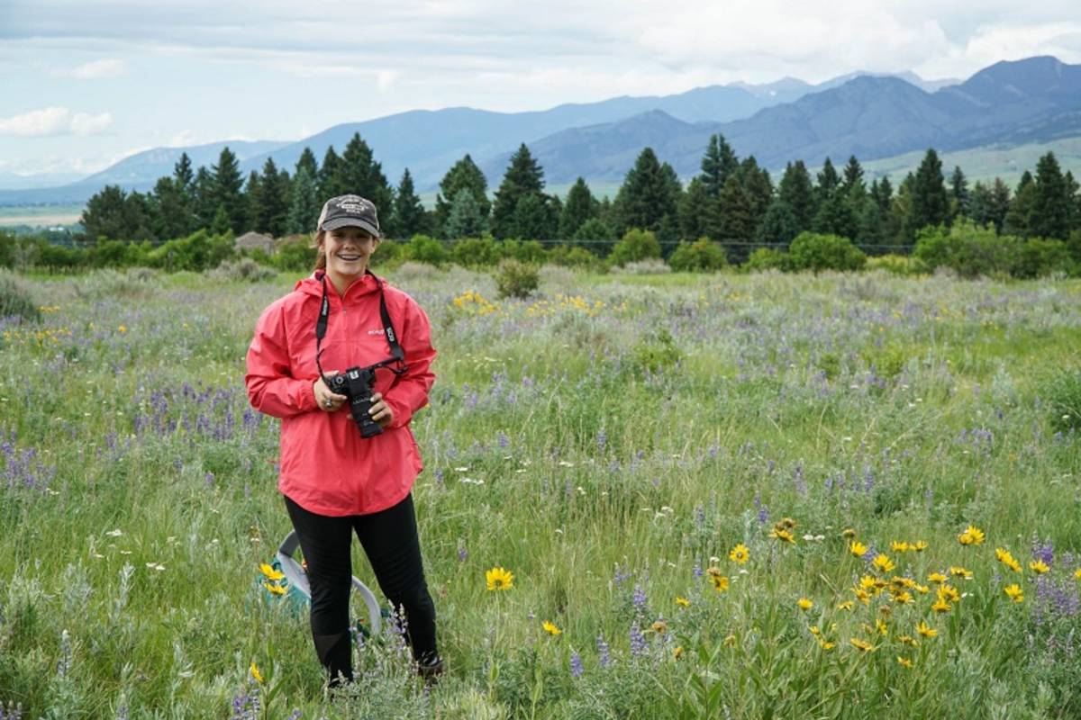 student with camera in field of flowers