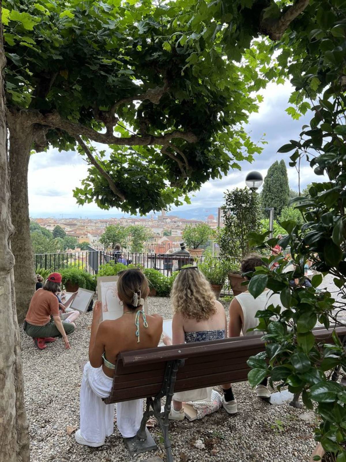 Students drawing in garden in Italy overlooking city skyline