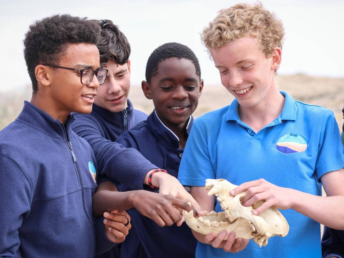 Students examining a hyena skull outdoors with LBS