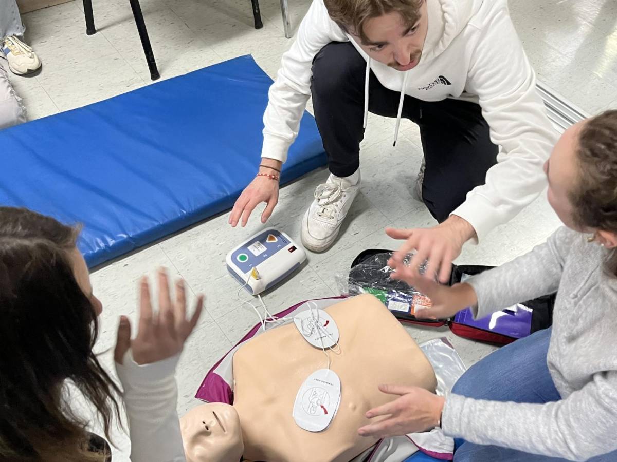 students in a Health Studies course gathered around a medical dummy