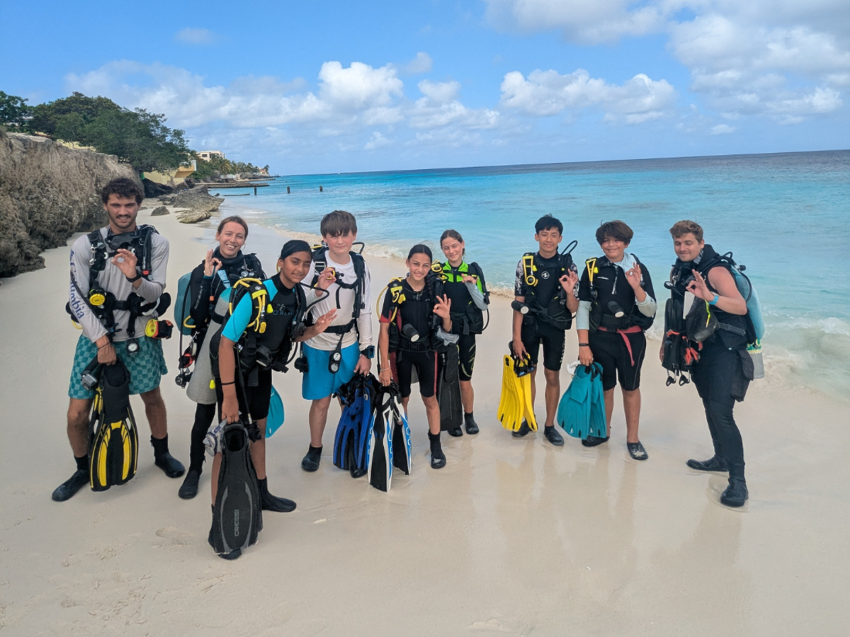 students in scuba gear stand on shore in Bonaire