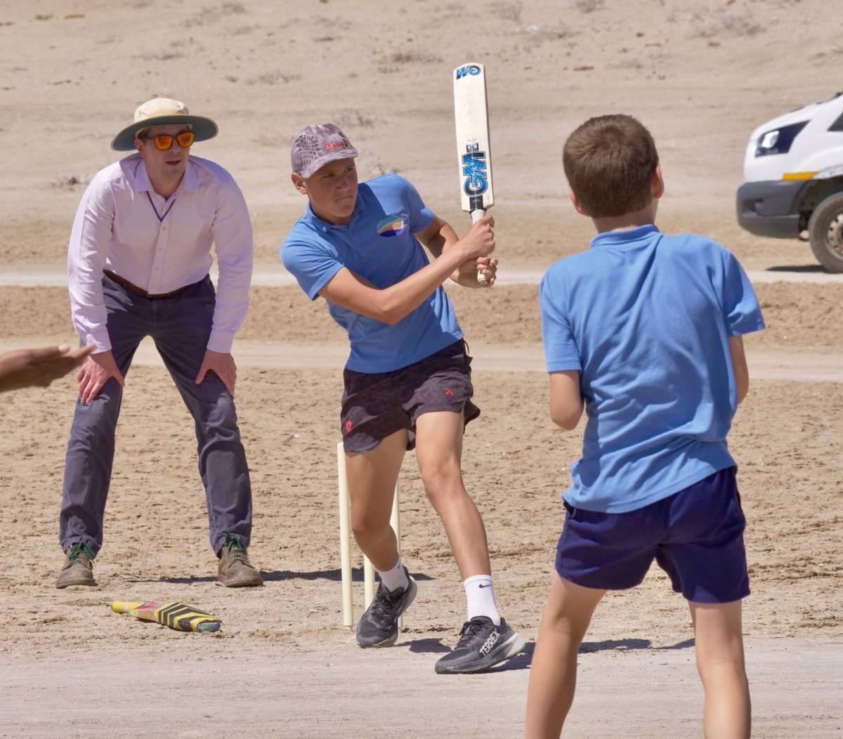 Students playing cricket on a sandy desert pitch, Lüderitz