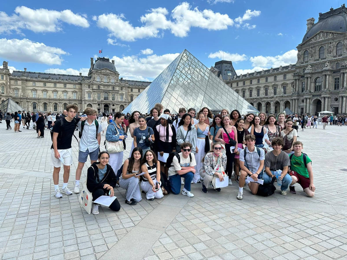 Students posing in front of the Louvre Museum