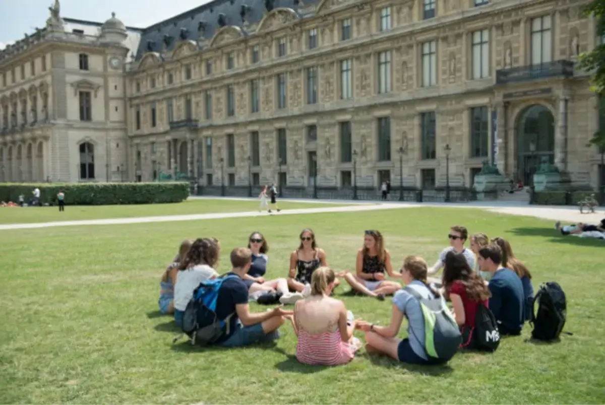 Students sit in a circle outside grand building 