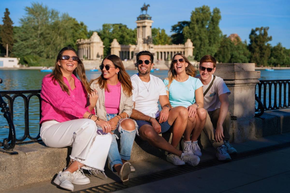 students sitting by railing of pond