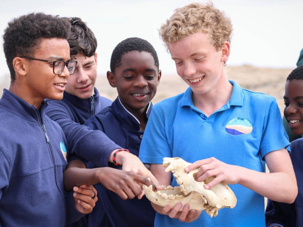 Students smiling whilst examining a brown hyena skull outside