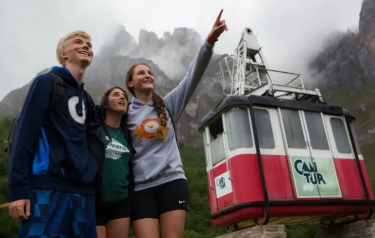 Students stand with cable car in mountains