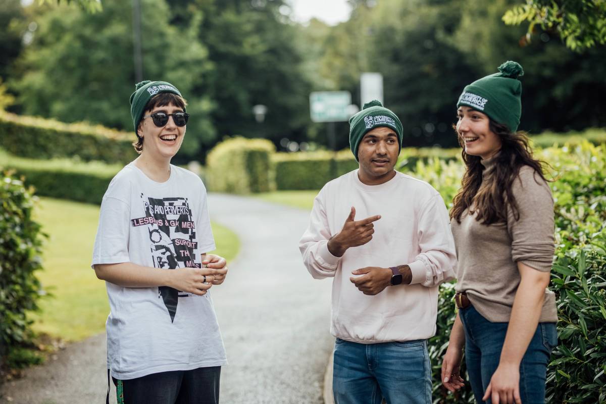 students wearing a green beanie with the University name