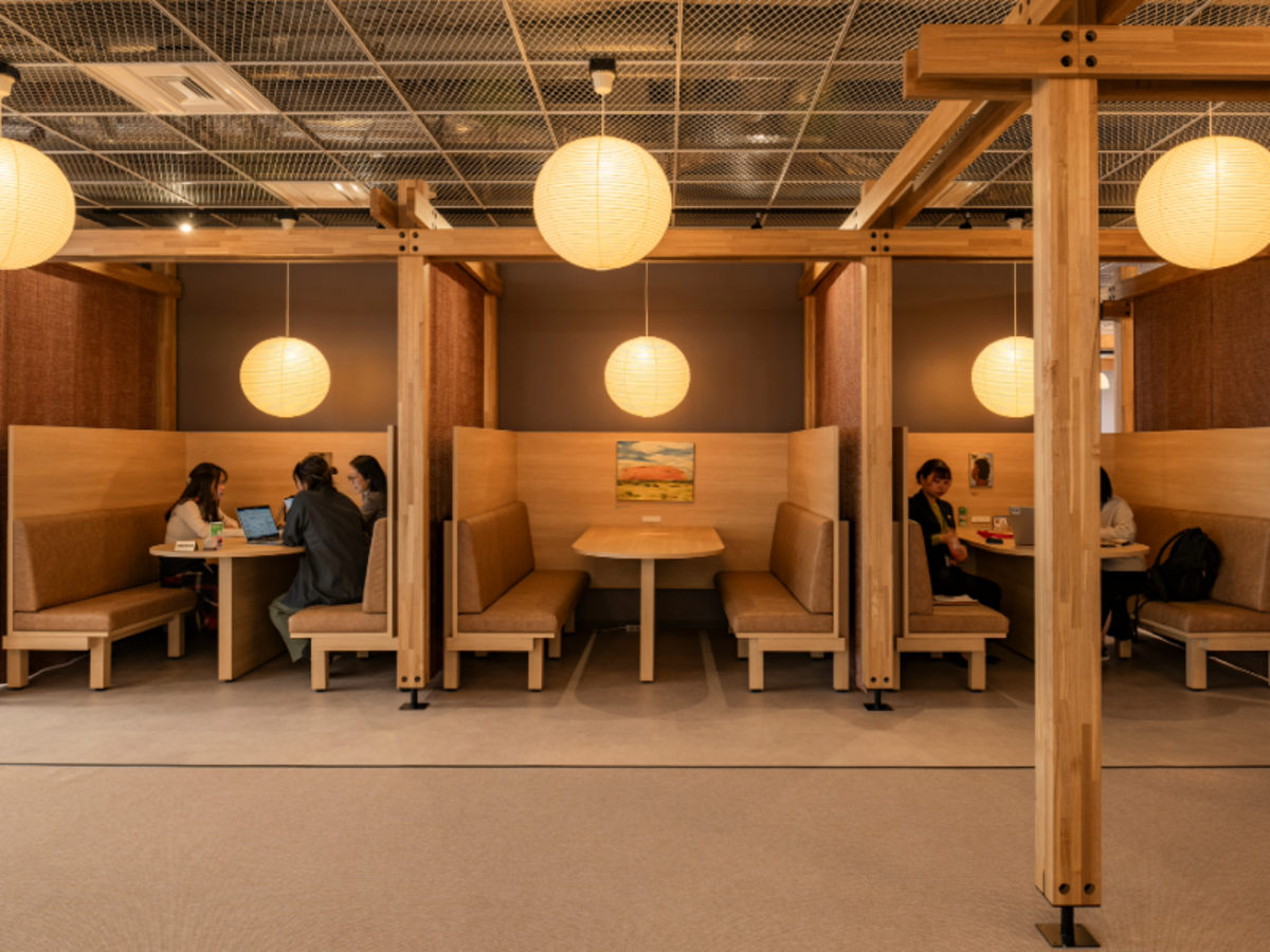Students working on laptops in modern wooden study booths at EF Tokyo’s campus.