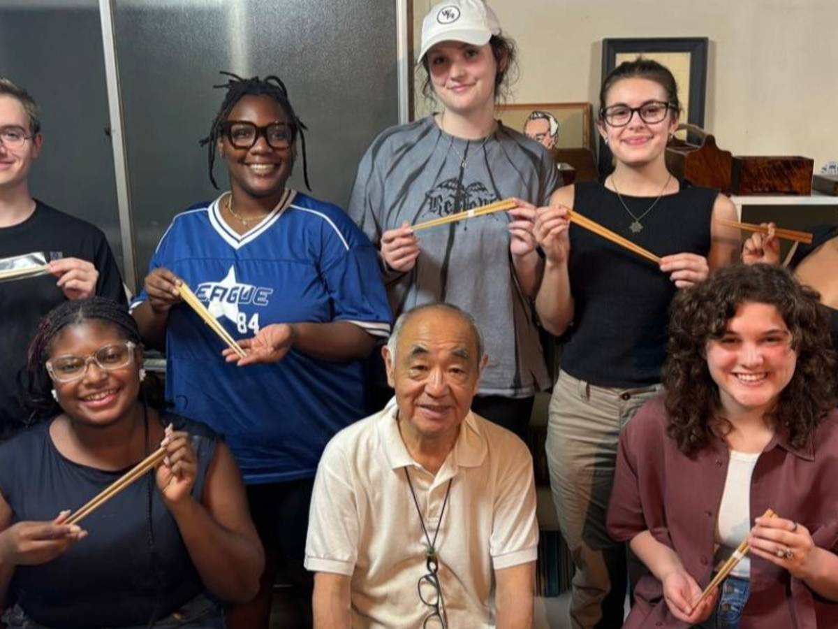 Sudents smiling with chopsticks during a cultural activity in Tokyo.