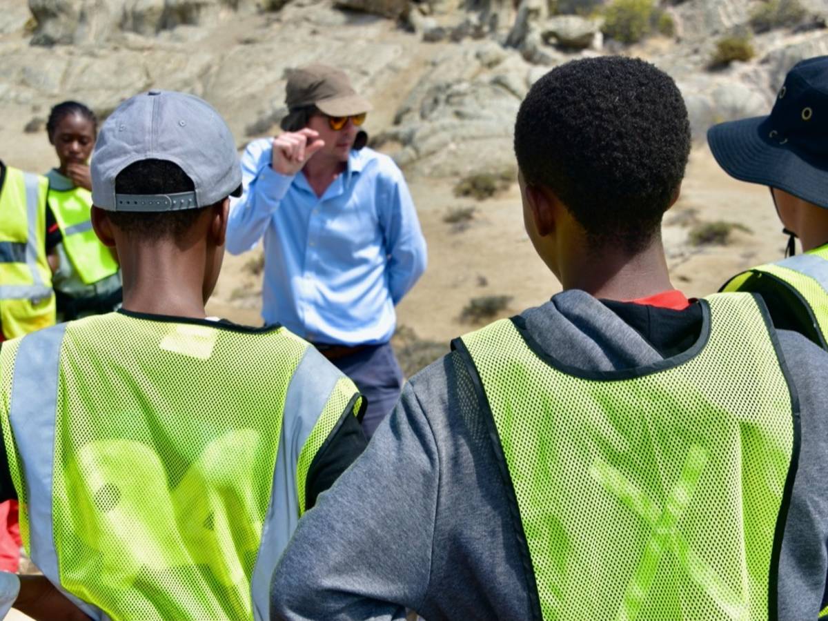 Teacher talking to students in the field.