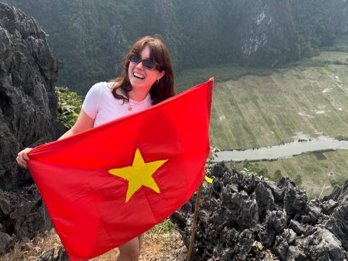 TEFL teacher exploring Ninh Binh, Vietnam while holding the Vietnamese flag during a weekend adventure.