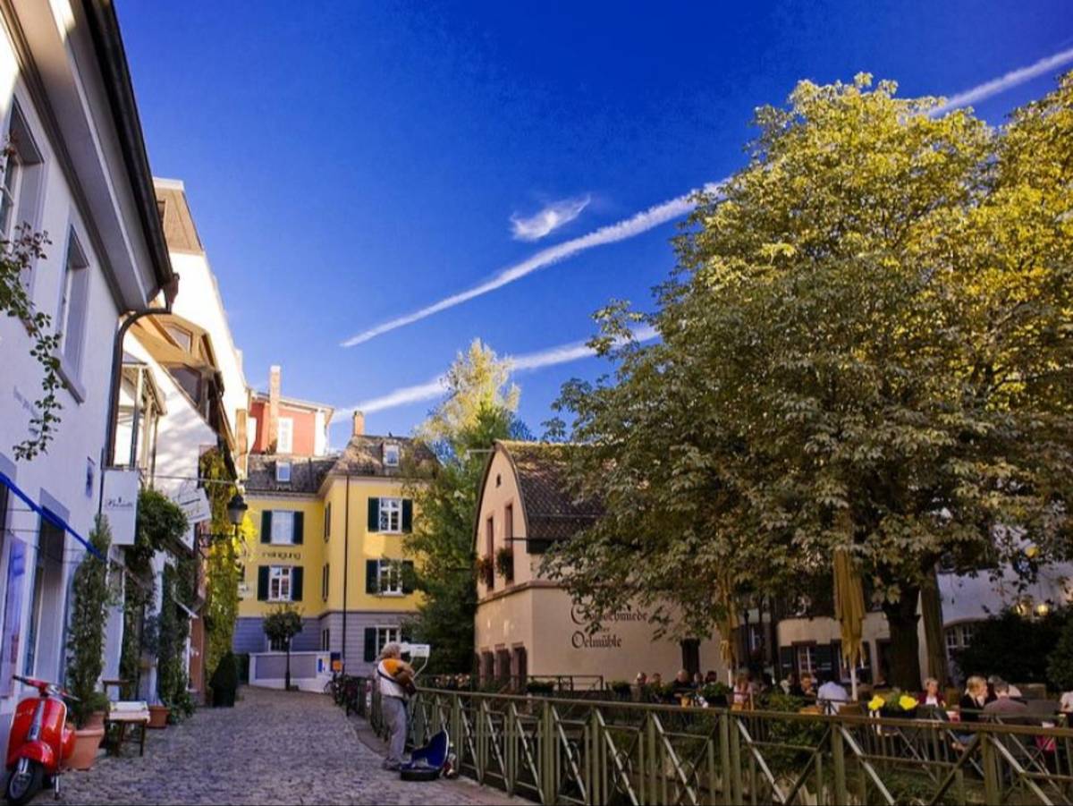 The cobblestone streets of Freiburg, Germany are lined with bright houses and storefronts.