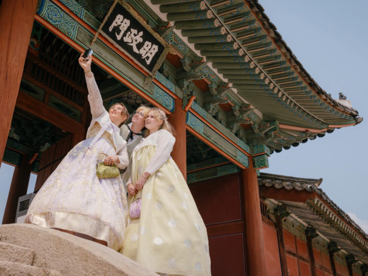Three EF Gap Year students dressed in colorful hanbok taking a selfie at a traditional palace in Seoul, South Korea, experiencing local history and culture.