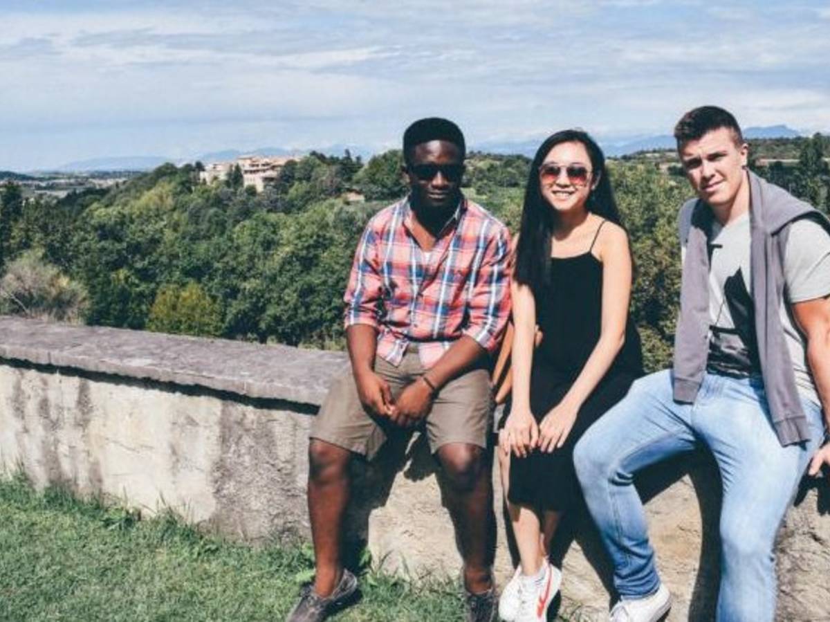 Three friends sitting on a stone wall at a park