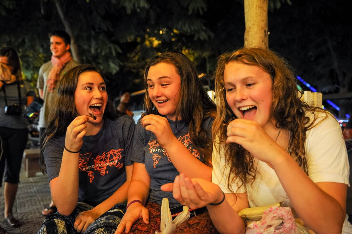 Three girls trying crickets in Cambodia