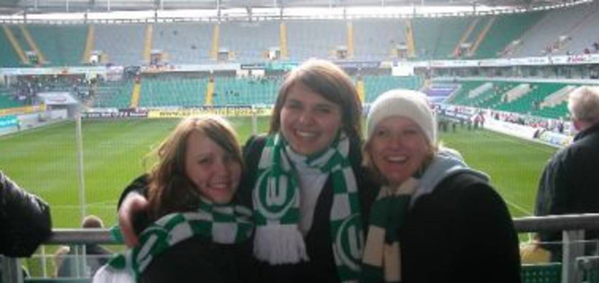 Three happy girls with a stadium on the background