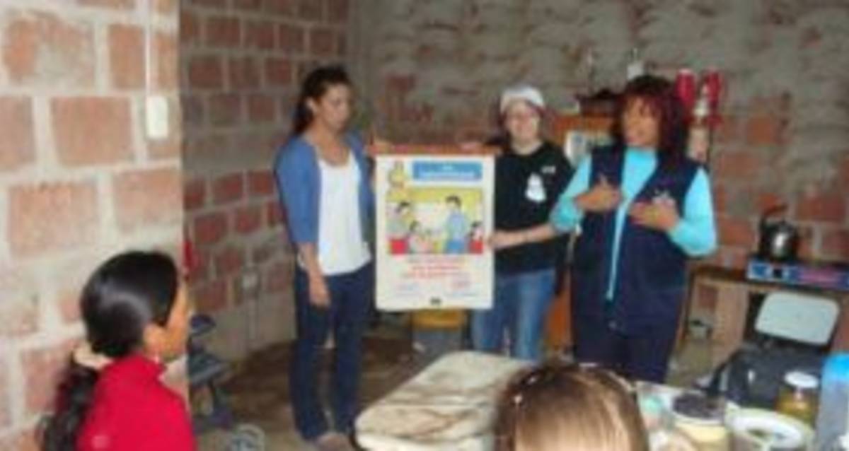 Three people conduct a presentation in a sparsely furnished room with brick walls