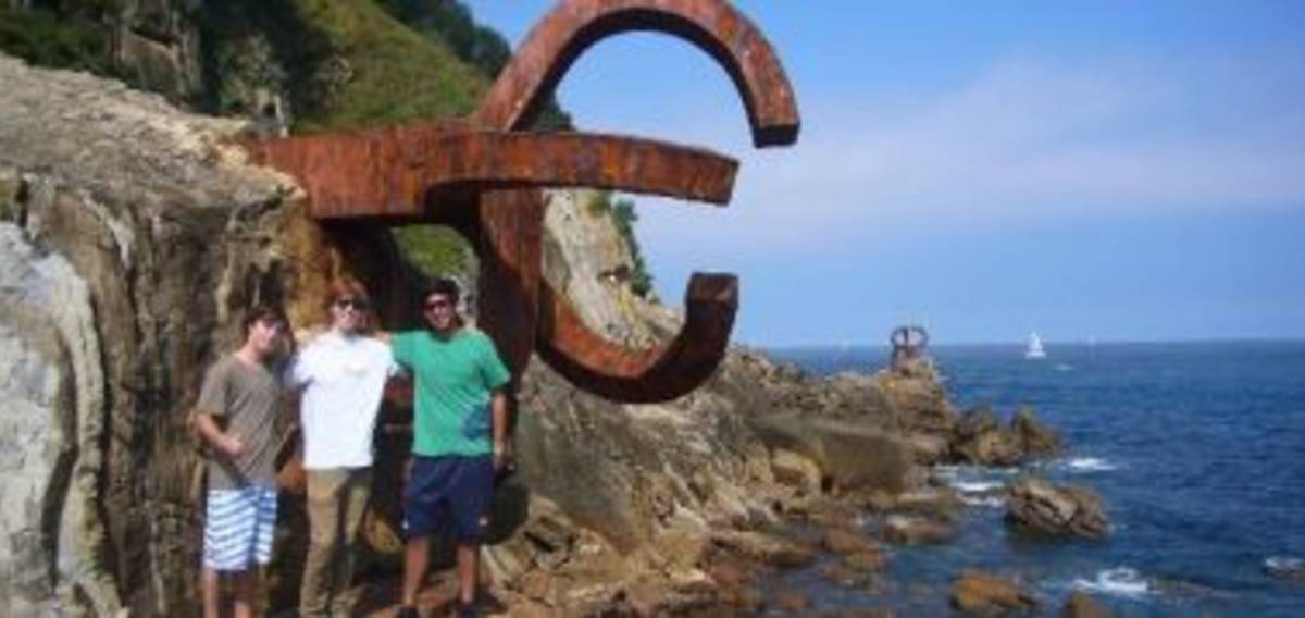 Three people on a rock by the ocean.