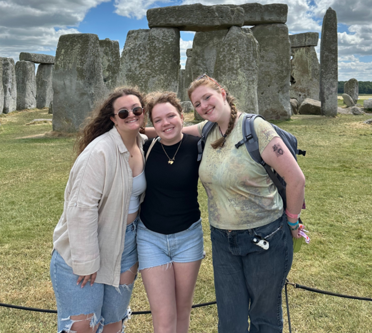 Three students in front of Stonehenge. 