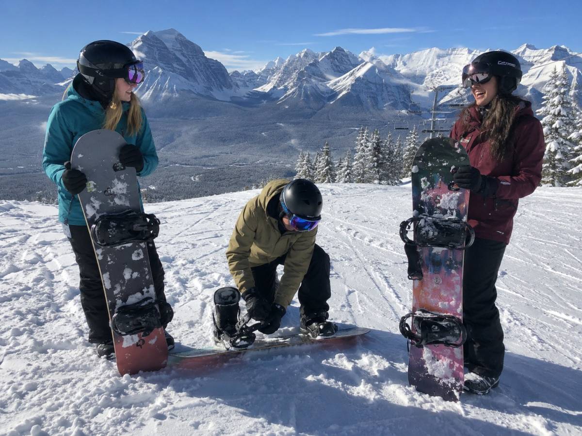 Three young snowboarders in the snow-covered Canadian Rockies