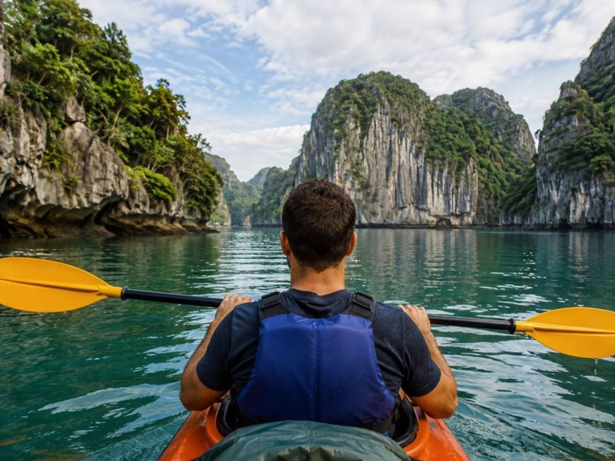 Traveller kayaking between limestone cliffs in Vietnam