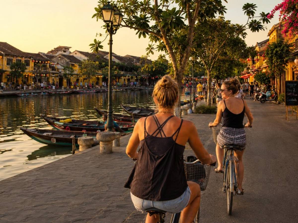Travellers cycling beside the river in Hoi An at sunset