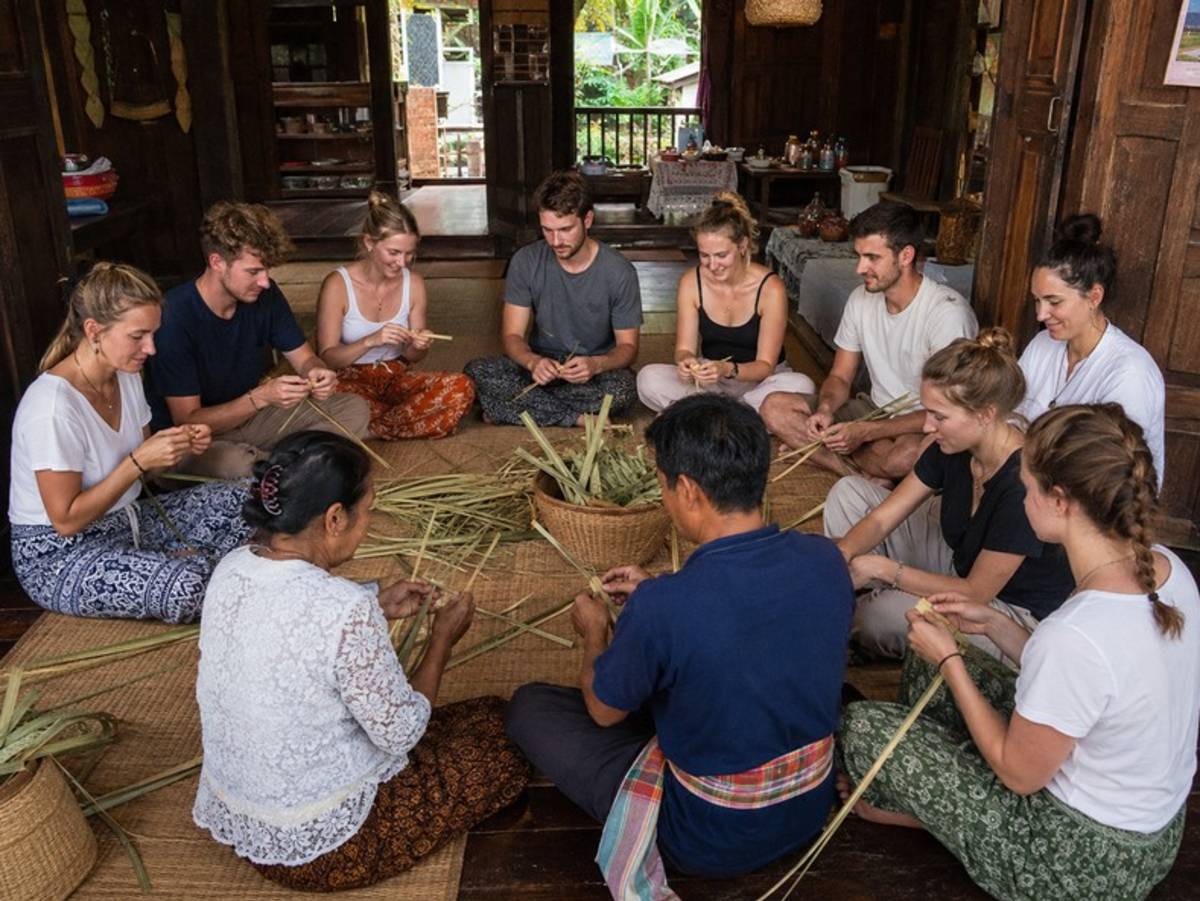 Travellers learning traditional weaving with local villagers
