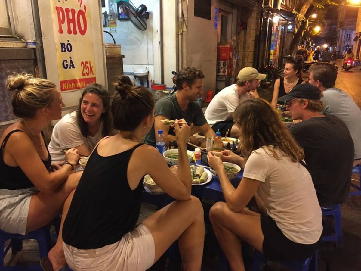 Travellers sharing Vietnamese food at a street stall
