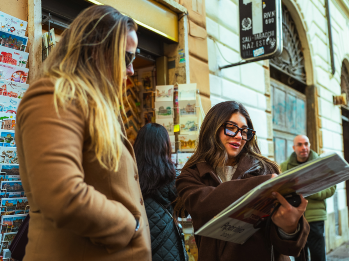 Two EF Gap Year students in Rome looking at postcards outside a street shop, enjoying local culture and city life during their study abroad experience.