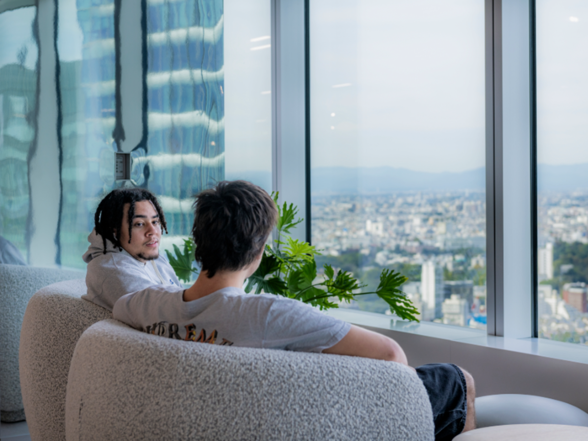 Two EF students relaxing by a large window with a panoramic view of Tokyo’s skyline.