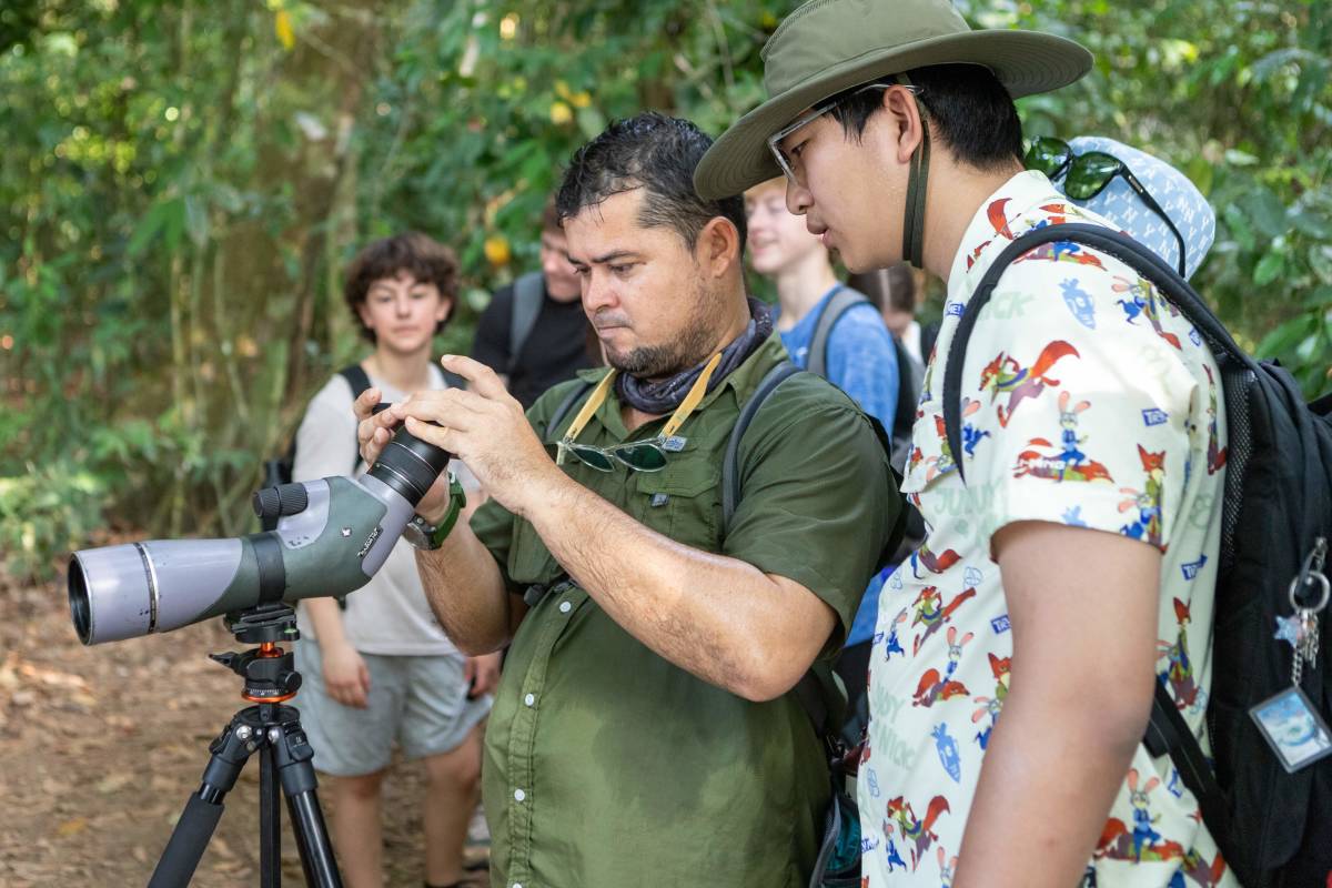 Two people look through a wildlife spotting scope. 