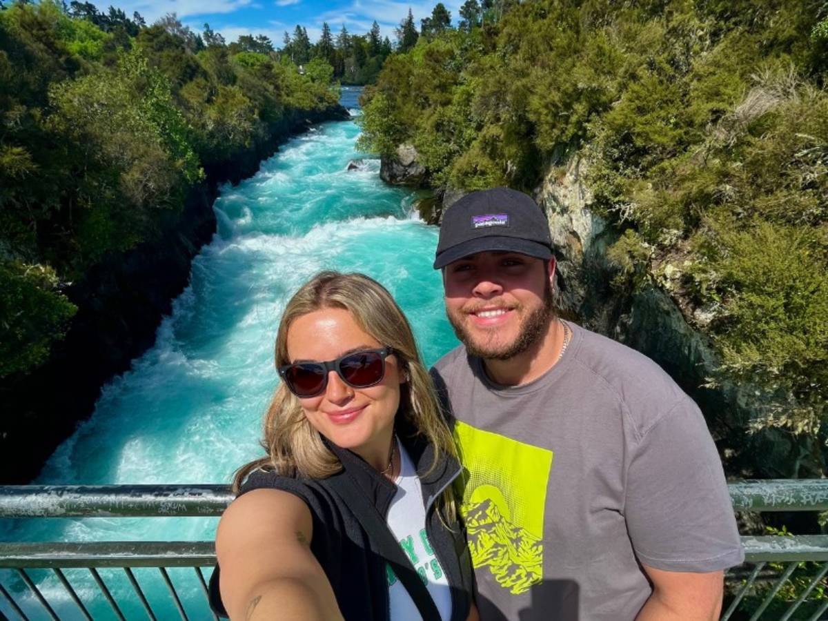 Two people standing on a bridge with a river in the background
