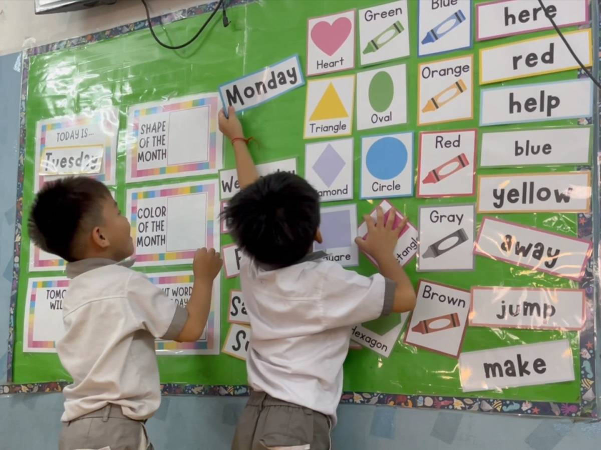 Two school boys move laminated cards on display board.