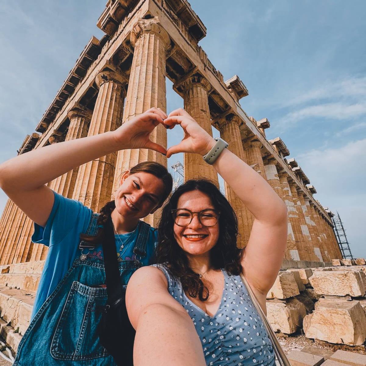 Two students at the acropolis making a heart with their hands