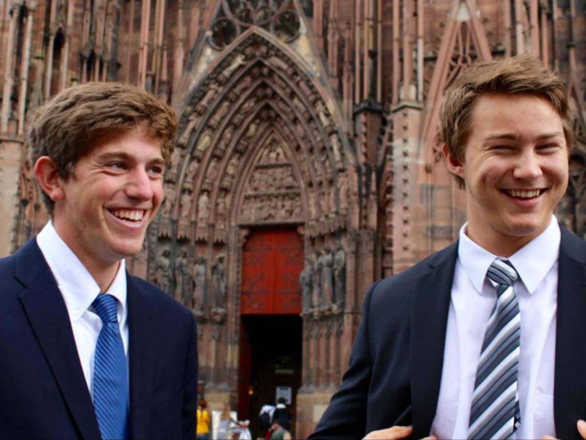 Two students in suits smiling in front of the cathedral in Brussels, Belgium.