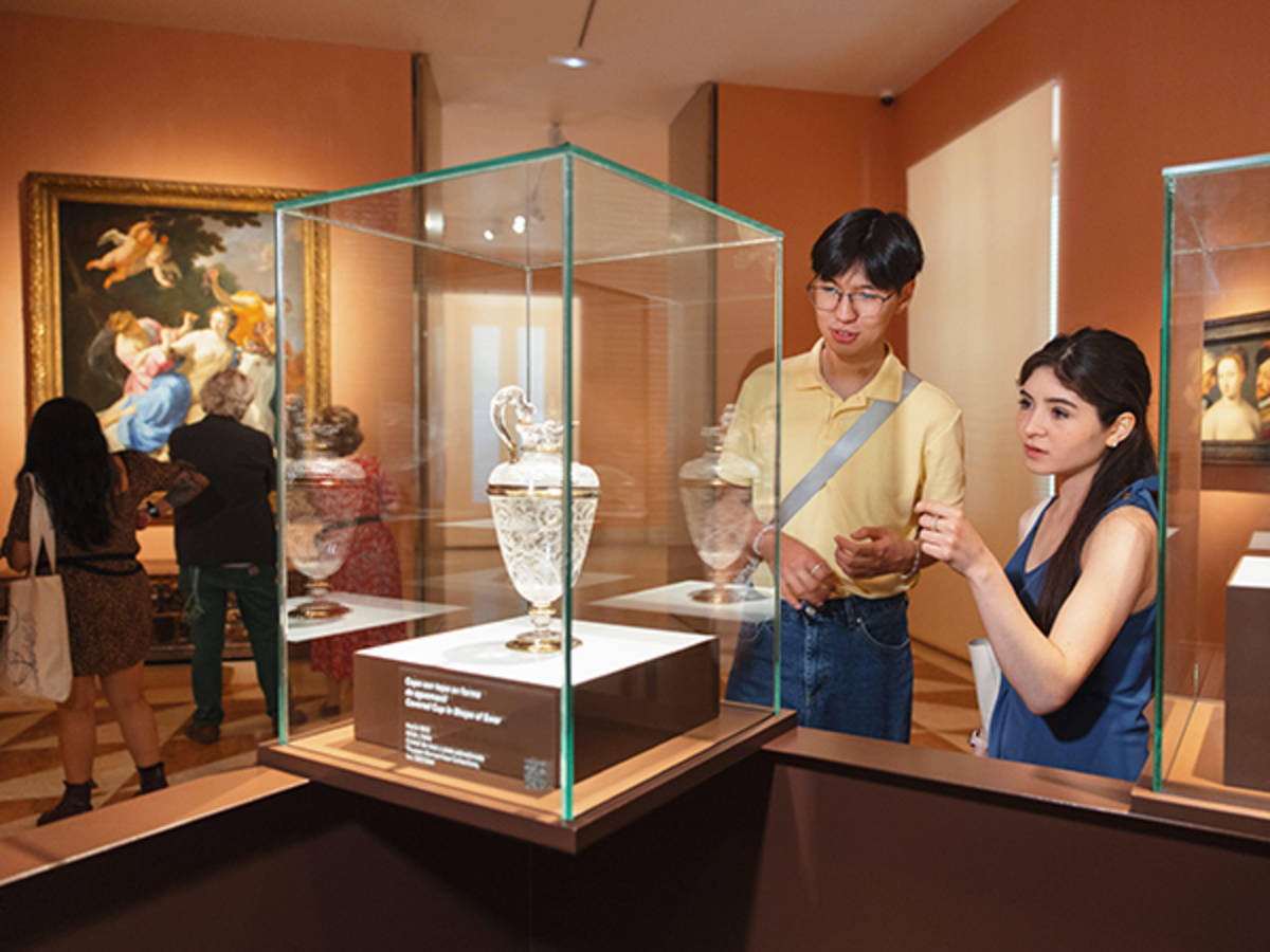 Two students look at a glass vase on exhibit in a museum